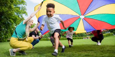 Kids playing with a colorful parachute outdoors.