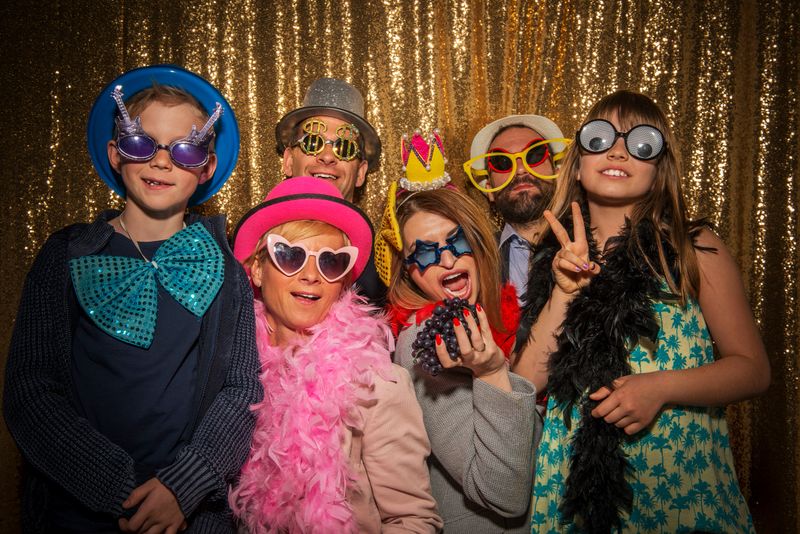 Portrait of cheerful male and female friends wearing party props and taking funny photo during the party.