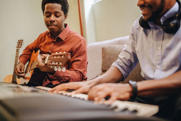 Two men playing guitar and keyboard together.