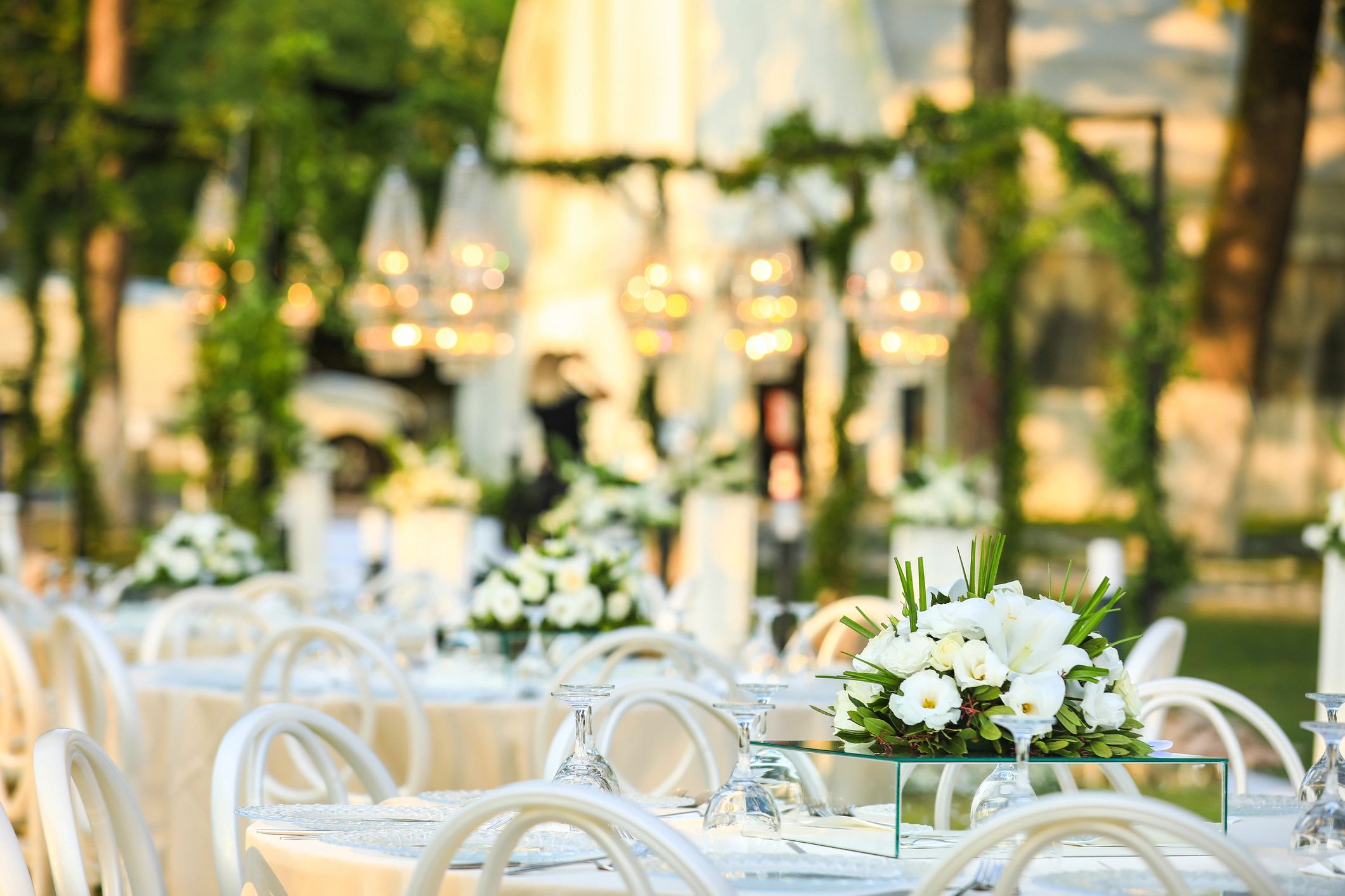 Elegant outdoor event setup with white floral centerpieces.