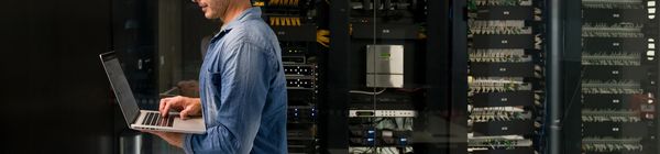 Technician working on laptop in server room.