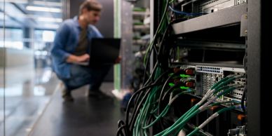 Man working on a laptop in a server room.