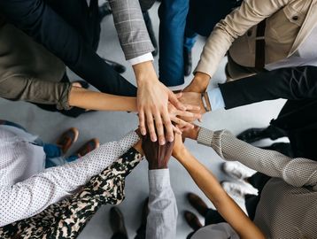 Diverse group stacking hands together in unity.