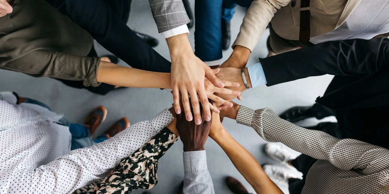 Diverse group of people stacking hands in unity.