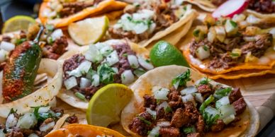 Close-up of assorted tacos with lime wedges.