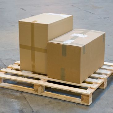 Two cardboard boxes on a wooden pallet in a warehouse.