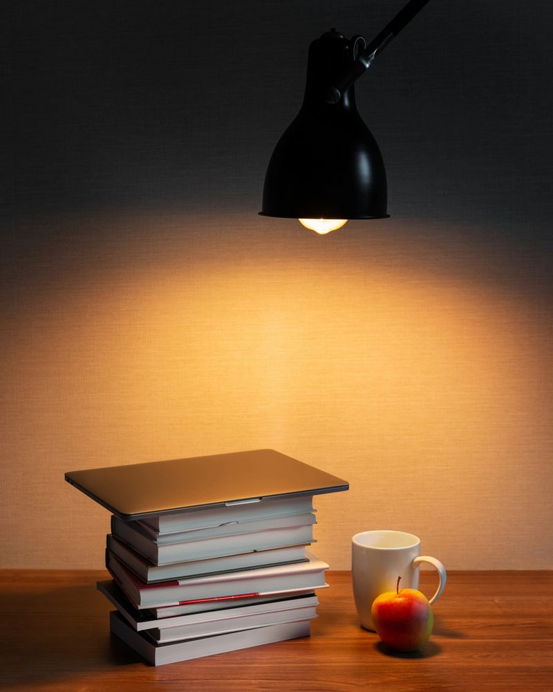a stack of books with a laptop and a cup of tea lie on the table