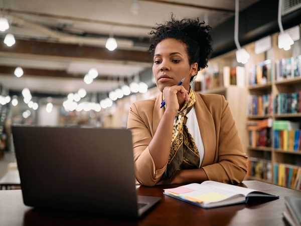 A woman working at her laptop in a library