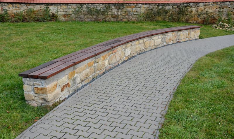 bent sandstone walls made of stone blocks serve as design elements, retaining walls, or seating areas, seats for park visitors. benches made of horizontal wood plank boards