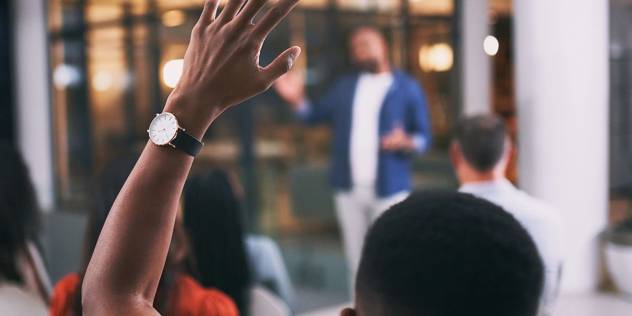 Person raising hand to ask question during presentation.