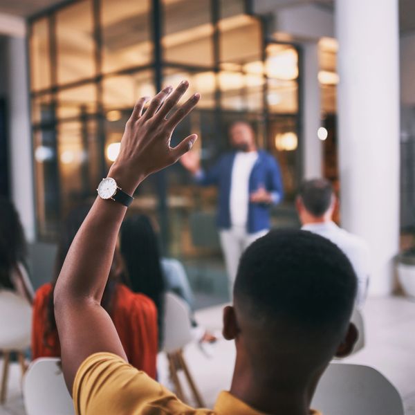A person raising their hand to ask a question in a seminar or meeting.