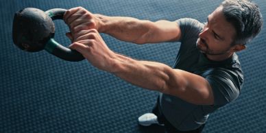 Man exercising with a kettlebell indoors.