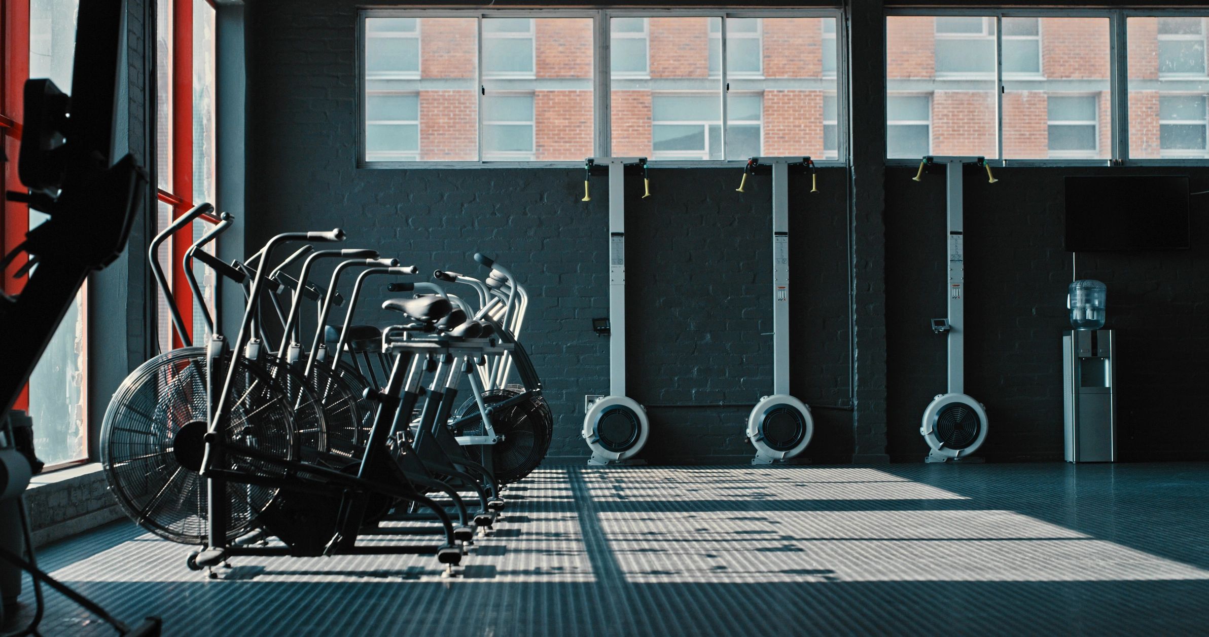 Empty gym with exercise bikes and rowing machines.