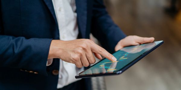 Person in a suit using a tablet displaying financial data.