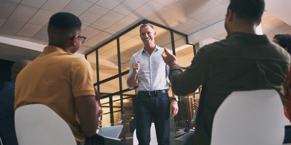 Man confidently speaking to a group in a modern office.