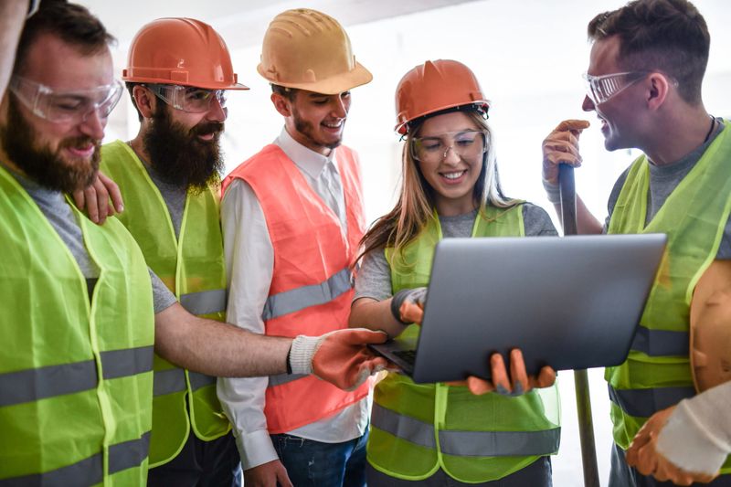 Happy Team Of Architect, Civil Engineer And Construction Workers Examining Building Projection