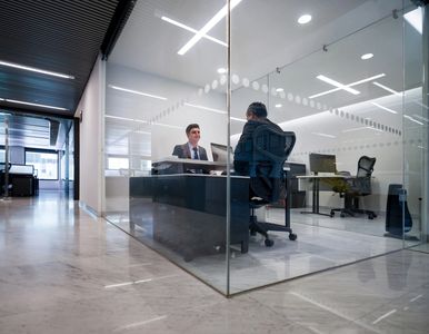 Two men having a meeting in a glass office.
