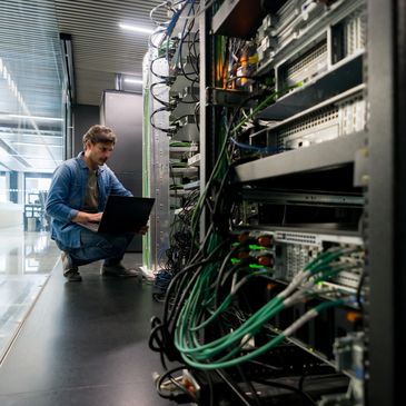 Technician working on server racks with a laptop in a modern data center.
