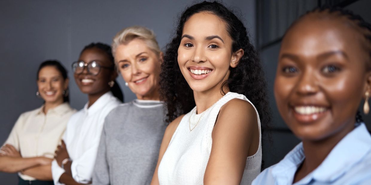 Diverse group of smiling women standing confidently in a line.