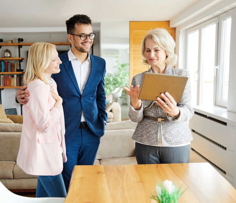 Young happy couple and an agent in a new property