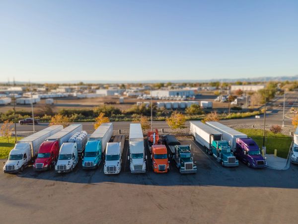 Line of colorful semi trucks parked in a lot on a clear day.