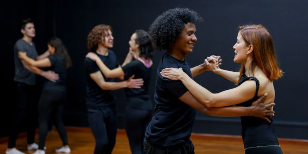 Couples dancing in a class with smiles.