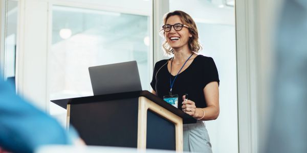 A woman smiling while giving a presentation.