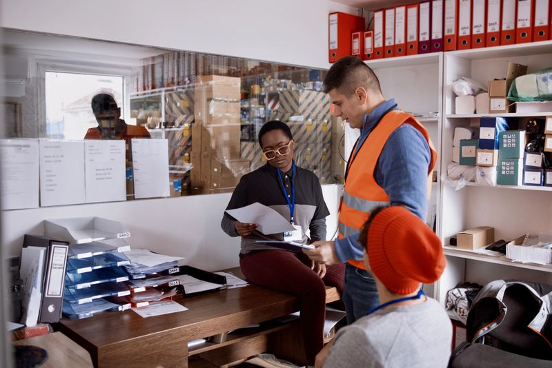 Delivery employees having a meeting with manager in distribution warehouse office