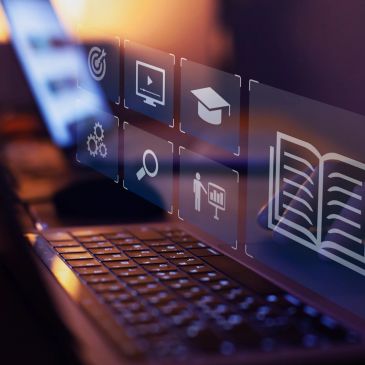 Digital education icons above a glowing laptop keyboard.