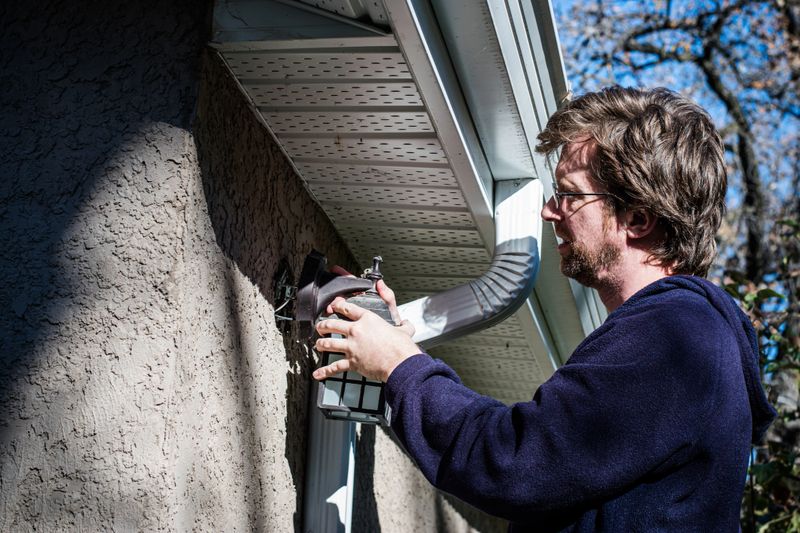 The contractor is installing a light fixture on the side of a garage