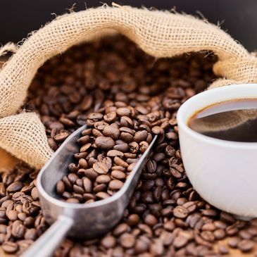 Coffee beans, a coffee scoop, and a cup of hot black coffee.