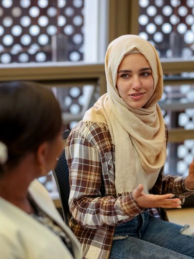 Two women engaged in a conversation indoors.