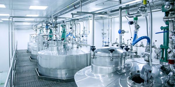 Clean industrial stainless steel tanks with pipes in a bright facility.