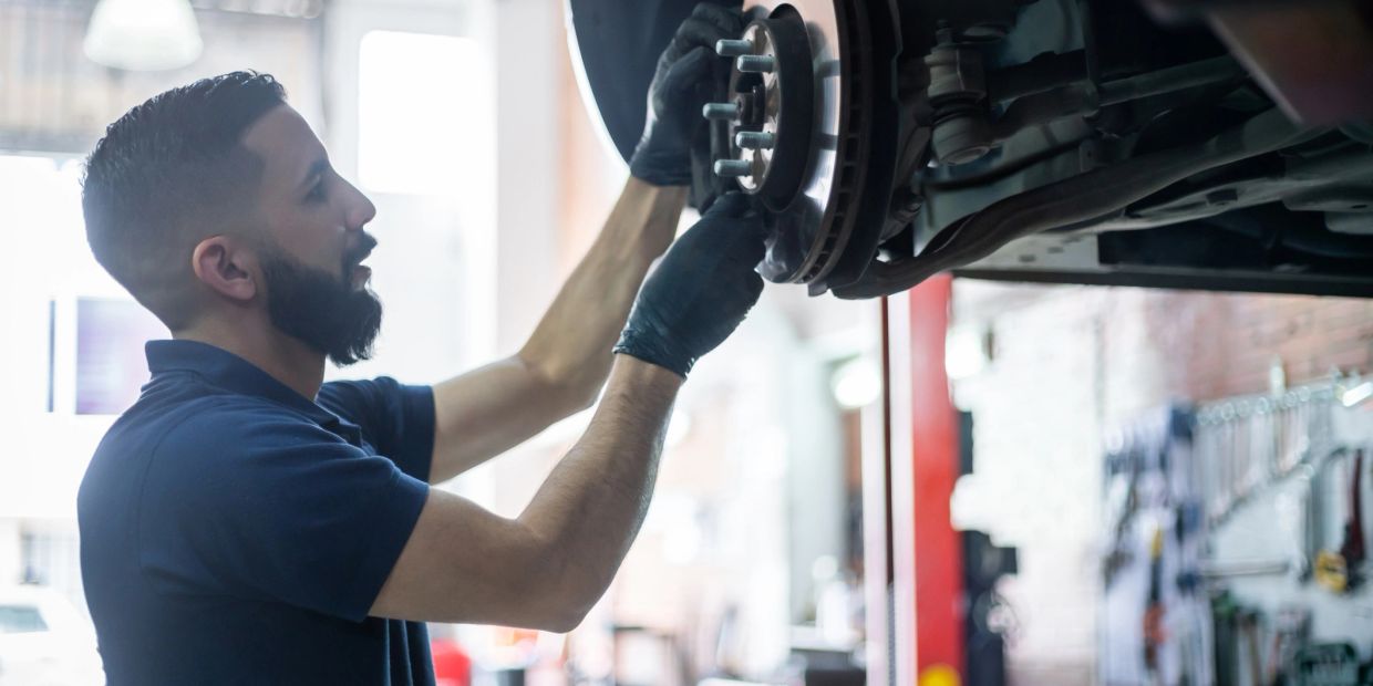 Mechanic repairing a car's brake system in a workshop.