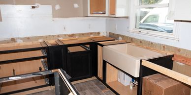 Partially installed kitchen cabinets with farmhouse sink during home renovation and remodel.