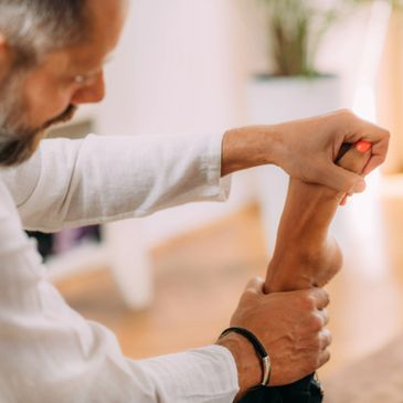 A man massaging a foot with painted nails indoors.