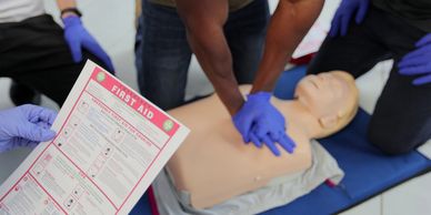 Person practicing CPR on a dummy guided by first aid instructions.