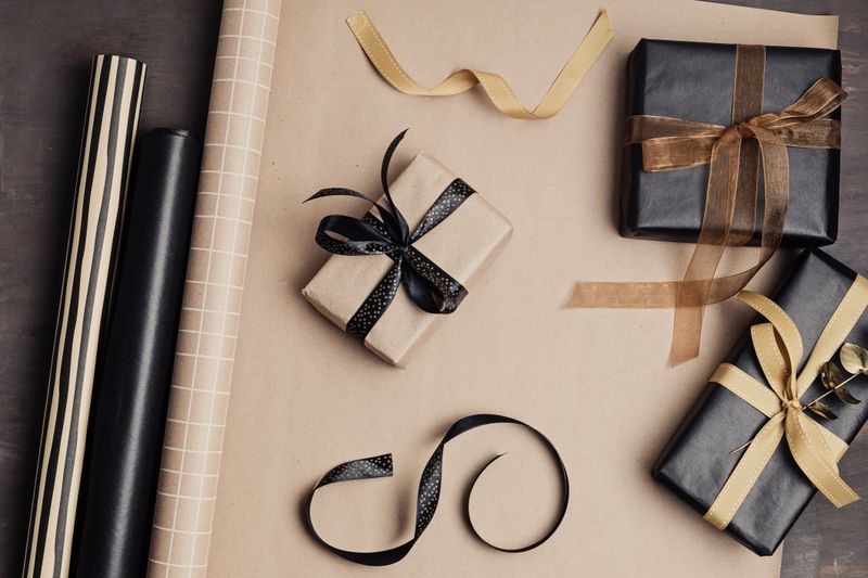 Christmas background with gift boxes and rolls of kraft wrapping paper. Xmas celebration, preparation for winter holidays. Festive mockup, top view, flat lay