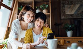 Two women enjoying a moment together while looking at a smartphone.