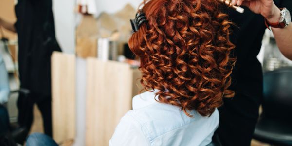 Person with beautiful curly red hair getting styled.