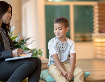 Woman engaging in a friendly conversation with a young boy indoors.