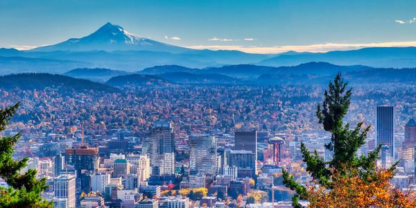 City skyline with mountain backdrop under clear sky.