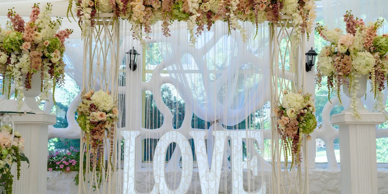 Elegant wedding arch with floral decorations and LOVE letters.