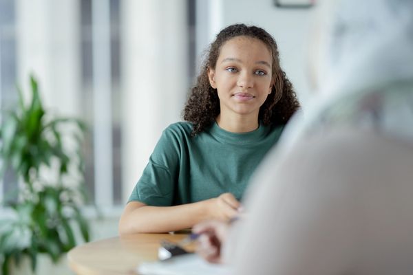 Young woman attentively listening during a conversation at a table indoors.