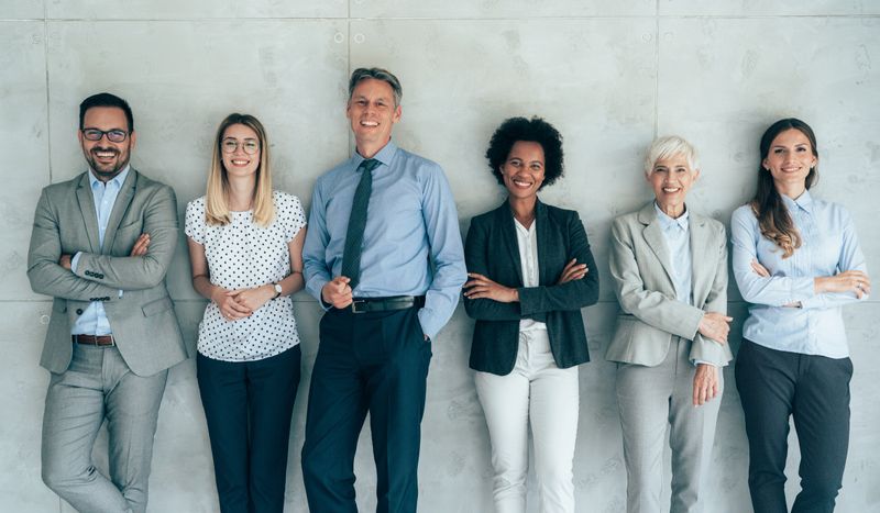 Multi-ethnic group of business persons standing in modern office and looking at camera