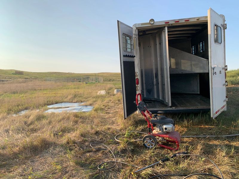 The open back door of a gooseneck slant load horse trailer that is clean and has been pressure washed, and the mats pulled to check the floor. Good yearly maintenance of your horse trailer is important, especially pressure washing.