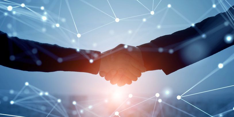 Hands shaking in a field of connected dots with bright light below.