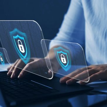 Hands typing on a laptop with digital security shields.