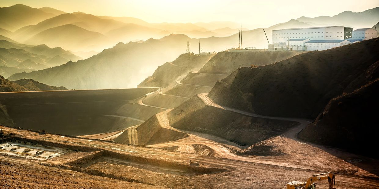 A large mining site with heavy machinery at sunrise.