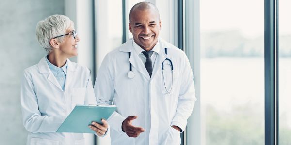 Dois médicos sorridentes conversando em hospital.